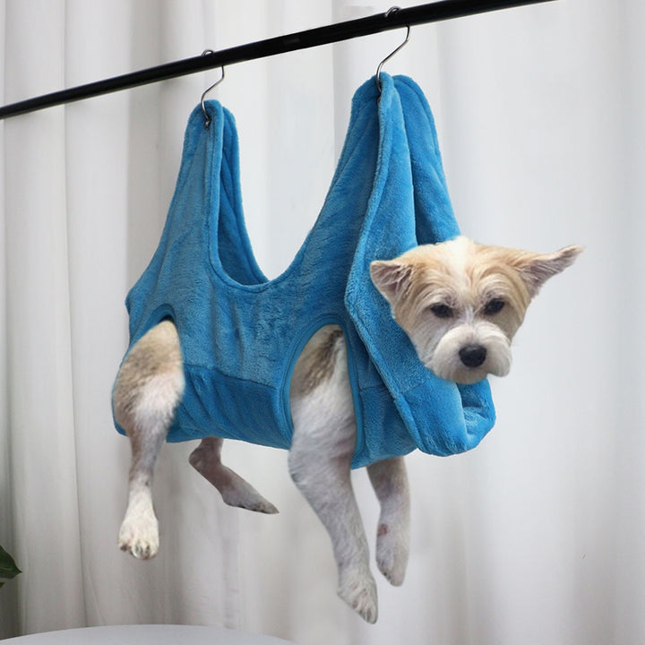 MATERA PET blue nail trimming hammock supporting a white terrier hanging from a grooming bar