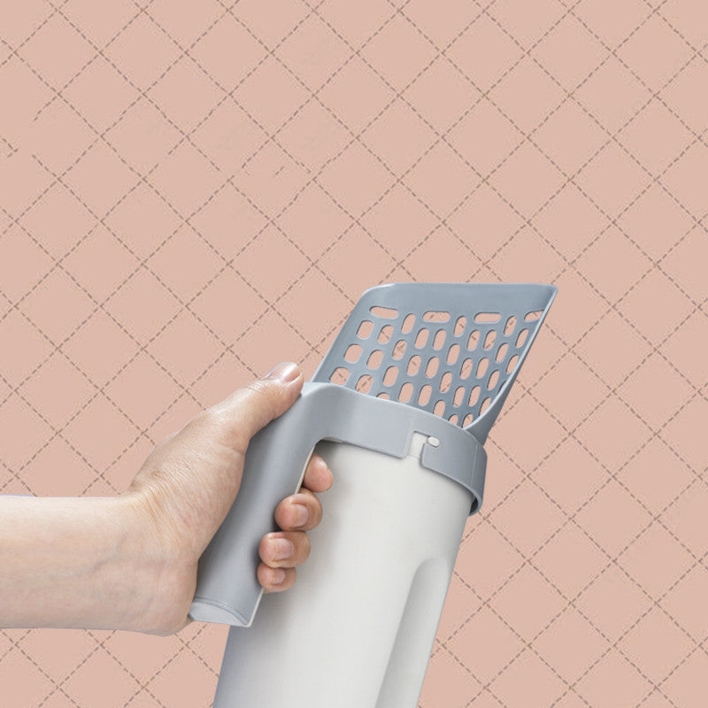 Hand holding the litter scoop by its long handle above the storage base